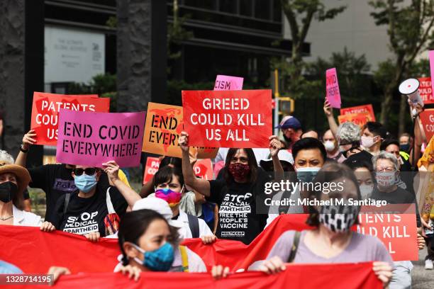 People gather for a protest demanding German Chancellor Angela Merkel, Pfizer, and wealthy nations make the coronavirus vaccine and treatments more...