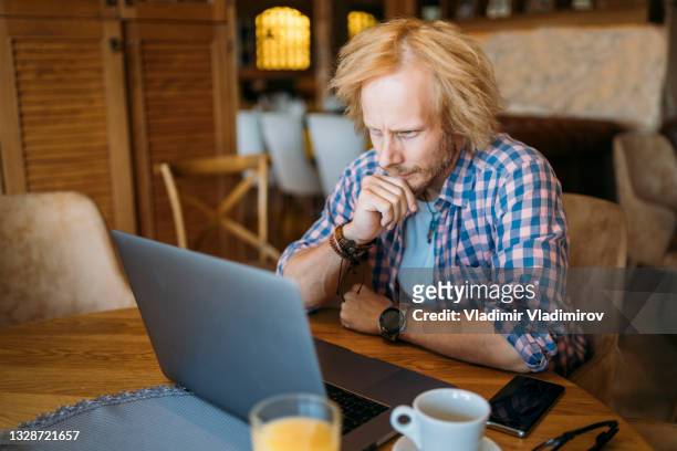 frustrated and worried young man contemplating alone in coffee shop. - person in front of computer stock pictures, royalty-free photos & images