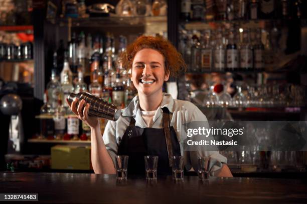 lächelnde barkeeperin, die getränke an der bar mixt - bartender mixing drinks stock-fotos und bilder