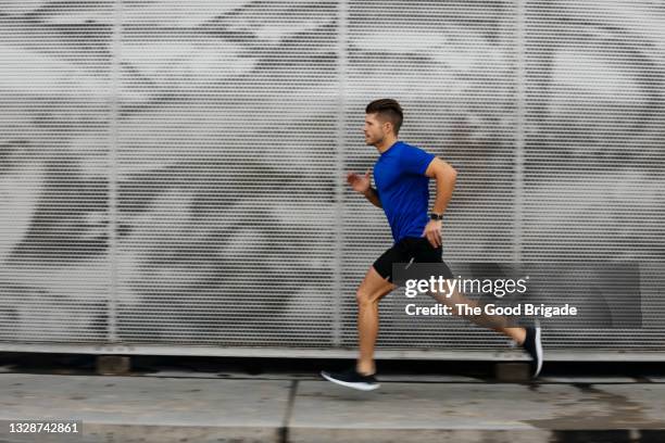 sportsman running against metal wall - uomini di età media foto e immagini stock