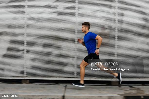 sportsman running against metal wall - correr imagens e fotografias de stock