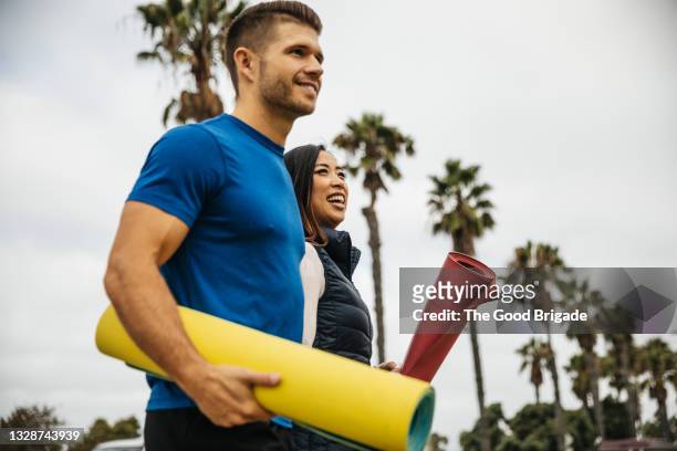 mid adult couple walking in park with yoga mats - asian couple walking stock pictures, royalty-free photos & images