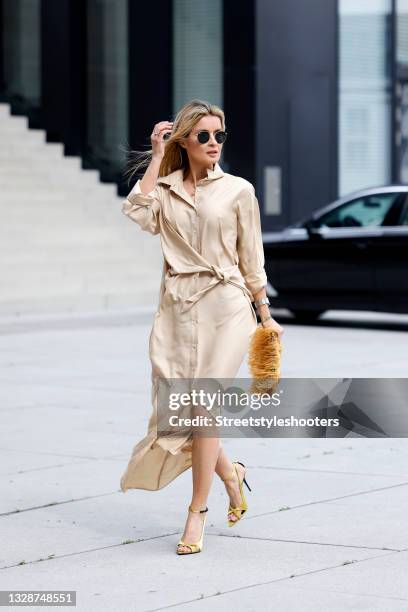 Influencer Gitta Banko wearing a beige longsleeve silk maxi shirt dress with tied waist by P.A.R.O.S.H., a brown-orange feather bag by...