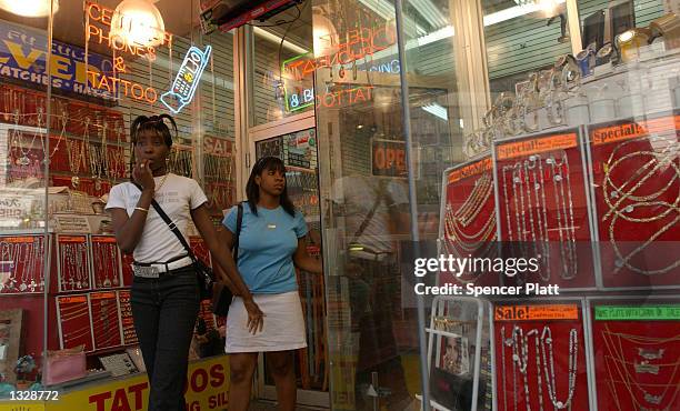 Women walk out of one of numerous stores that sell removable gold tooth caps, or fronts as they are called on the street, June 29, 2001 in Brooklyn,...