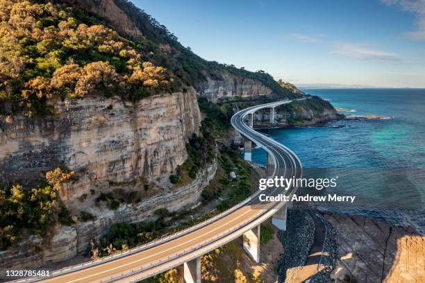 sea cliff bridge, rocky coast road, highway and mountain, aerial view - kust karakteristiek stockfoto's en -beelden