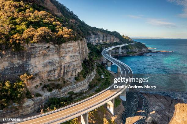 sea cliff bridge, rocky coast road, highway and mountain, aerial view - australian coastline stock pictures, royalty-free photos & images