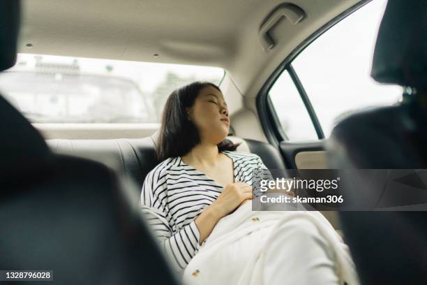 asian young adult mother exhausted and urgent breastfeeding  her daughter inside the car  at parking lot - pregnant woman car stock pictures, royalty-free photos & images