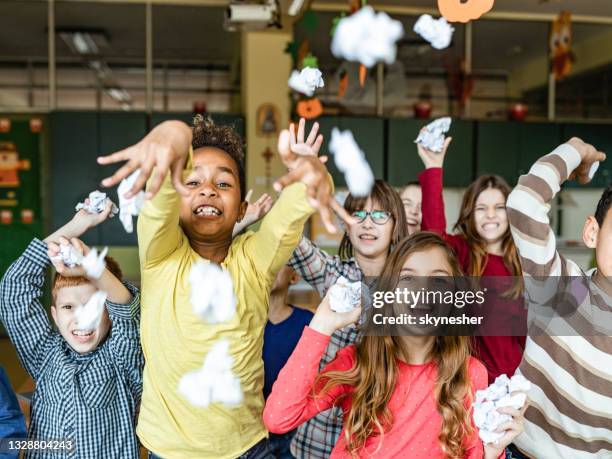 rude school children throwing crumpled papers on a teacher in the classroom. - paper ball stock pictures, royalty-free photos & images