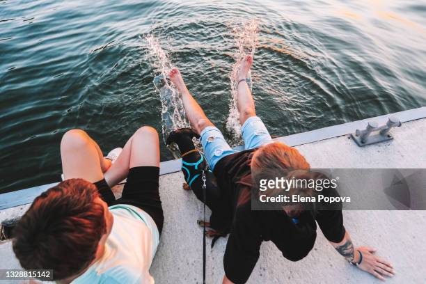 Young Adult Female Couple Relaxing With Cute Dachshund At The Dock