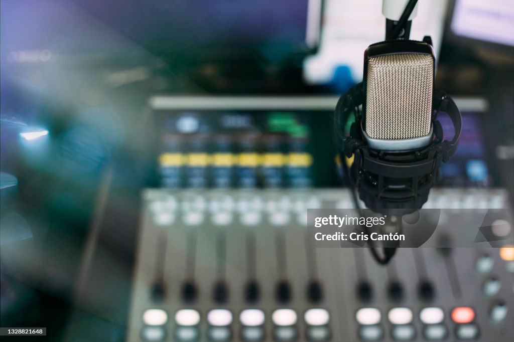 Radio broadcast studio with microphone and sound mixer console on the background