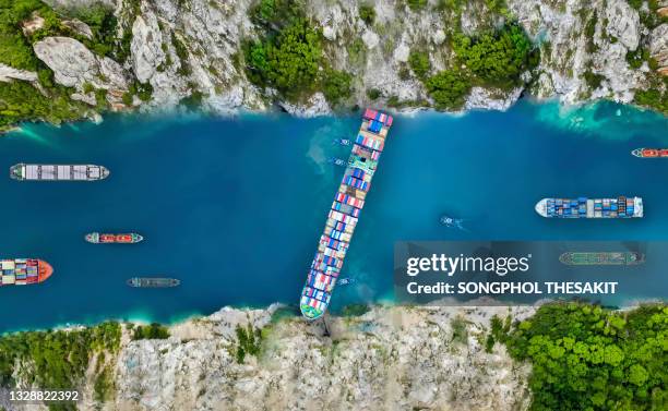 aerial view/a large cargo ship swept through the waterways in the suez canal, making it impossible for other ships to go. - marine marchande photos et images de collection