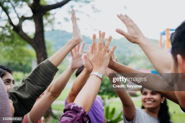 multi ethnic asian people giving each other a high five - five friends unity stock pictures, royalty-free photos & images