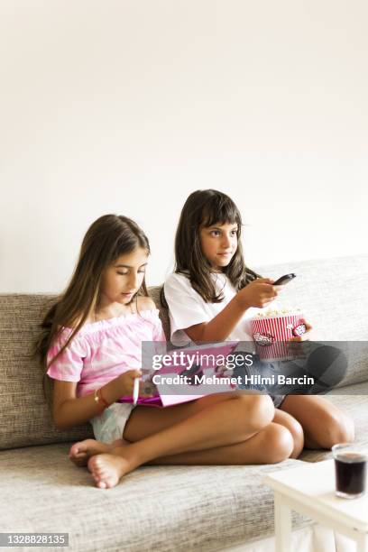 ragazza carina che guarda la tv con la sua amica a casa - famiglia multimediale foto e immagini stock