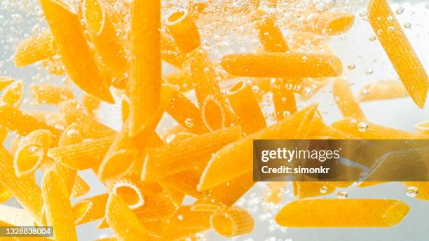 penne pasta falling into boiling water - boiling pasta stock pictures, royalty-free photos & images