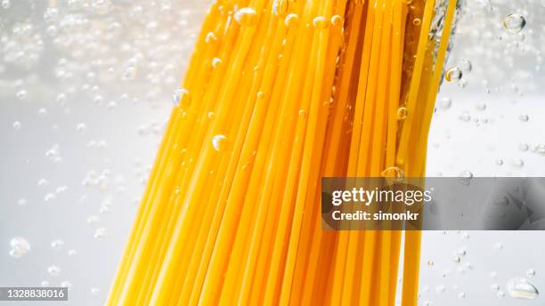 spaghetti falling into boiling water - boiling pasta stock pictures, royalty-free photos & images