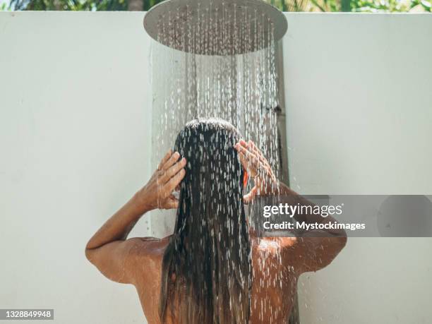 mulher toma banho ao ar livre em jardim tropical - tropical tree - fotografias e filmes do acervo