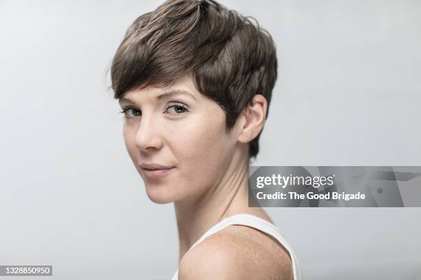 portrait of confident young woman on gray background - peinado pixie fotografías e imágenes de stock