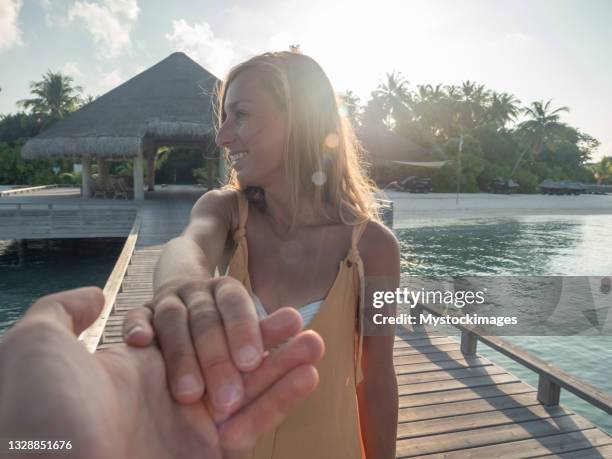 pov von paar, das sich bei sonnenuntergang auf einem hölzernen pier an den händen hält, tropische ferien - indian ocean stock-fotos und bilder