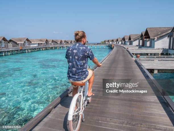 young man with bicycle on wooden pier in the maldives - maldives sport stock pictures, royalty-free photos & images