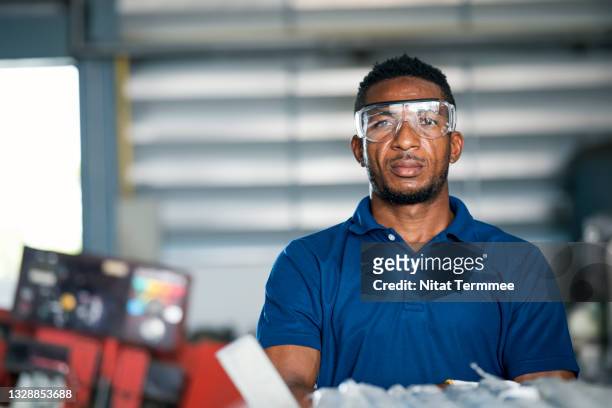 portrait of a african american warehouse worker is working in a factory raw material storage room. material supply for the production process. - production line worker stock pictures, royalty-free photos & images