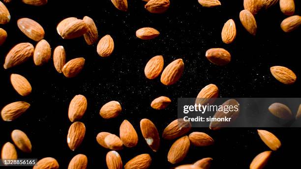 almonds falling onto black surface - almond stock pictures, royalty-free photos & images