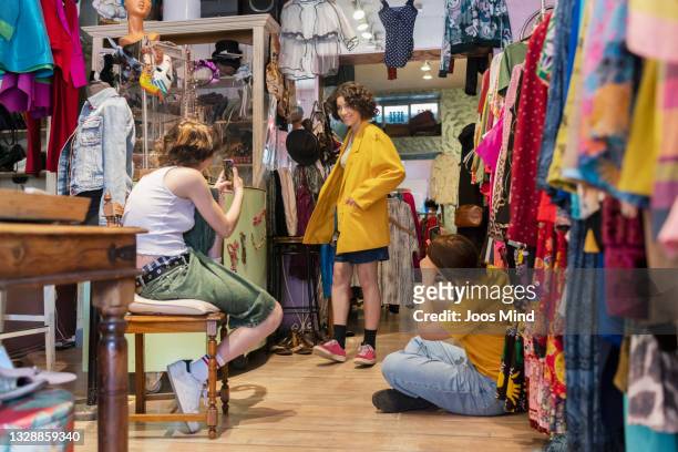 three teenager having fun in a second hand store - second hand fotografías e imágenes de stock