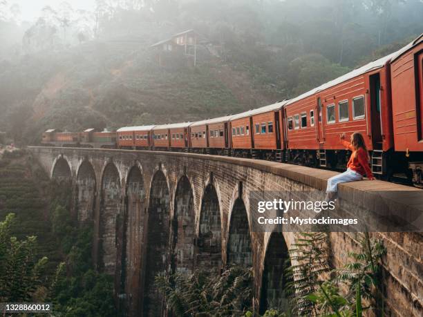 tourist hanging on viaduct bridge in sri lanka, train passing - sri lanka people stock pictures, royalty-free photos & images