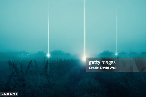 a moody science fiction concept, of ufo light beams landing in a field coming down from the sky. on a foggy spooky night. - extraterrestre photos et images de collection