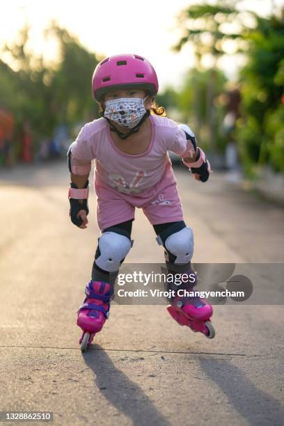 baby girl playing roller skate - kniebeschermer stockfoto's en -beelden