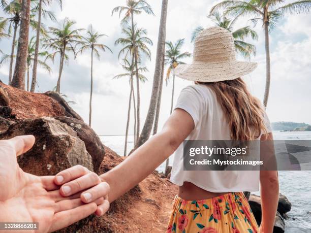 couple holding hands on mountain palm tree hill - love on the rocks stock pictures, royalty-free photos & images