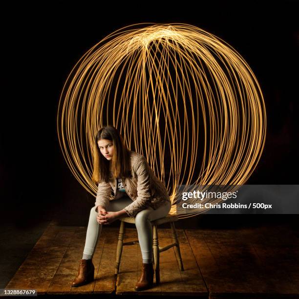 teen girl sitting on chair with light painting behind her,launceston,united kingdom,uk - portrait blurred background stockfoto's en -beelden