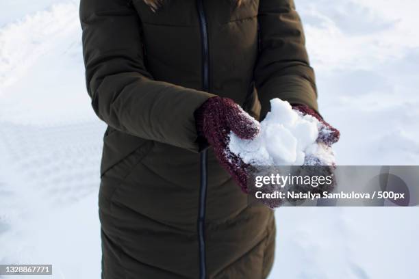 young woman holding snow in her hands in mittens - woman hands in mittens stock-fotos und bilder