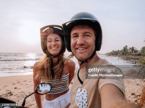 couple take selfie on scooter by the beach at sunset - dirt road motorbike stock pictures, royalty-free photos & images