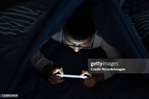 latin boy is in his room playing on his cell phone - mobile game stock pictures, royalty-free photos & images