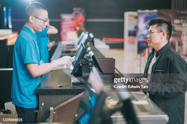 el público masculino adulto medio chino asiático en el mostrador de boletos delantero comprando palomitas de maíz bebida antes de la hora del espectáculo de cine en el cine de cine - ticket counter fotografías e imágenes de stock