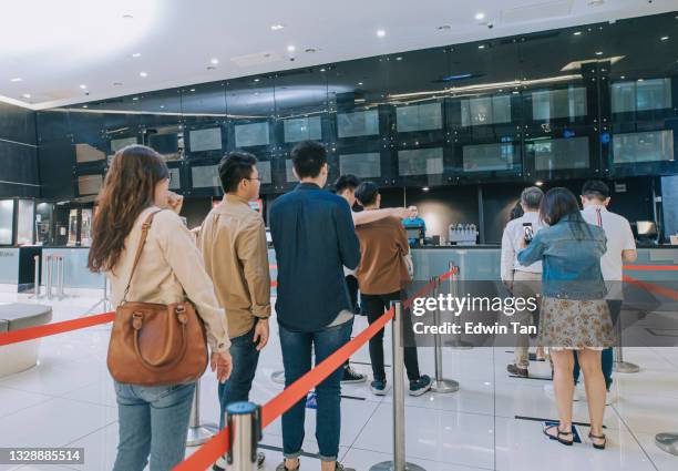 asiatisches chinesisches publikum, das vor dem ticketschalter schlange steht und kinokarten kauft und popcorns vor der kinovorführung kontaktlos bezahlt - fahrkartenschalter stock-fotos und bilder