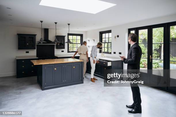 prospective home buyers examining features of luxury kitchen - checking stockfoto's en -beelden