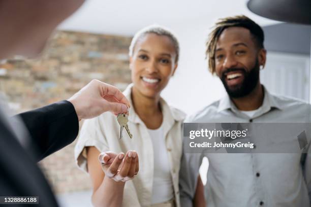 new home owners smiling as real estate agent gives them keys - house key hands stock pictures, royalty-free photos & images