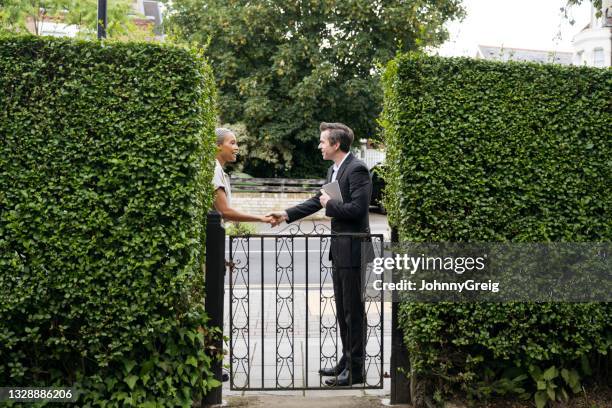 real estate agent shaking hands with prospective buyer at front gate - property boundary stock pictures, royalty-free photos & images