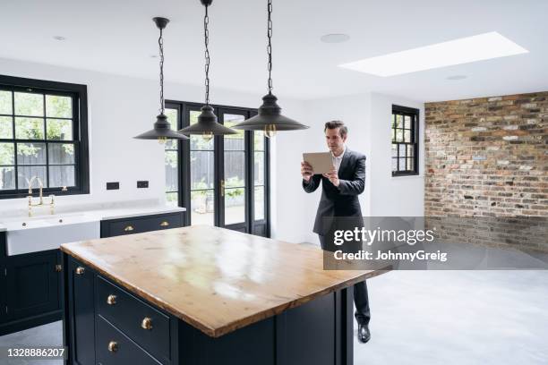 male estate agent using digital tablet to photograph kitchen - sold engelskt begrepp bildbanksfoton och bilder