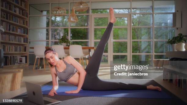 deportista haciendo tablón en colchoneta de yoga con portátil. entrenamiento en casa - gluteos fotografías e imágenes de stock