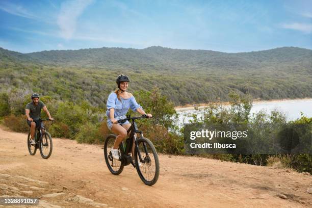 couple using e-bike in tuscany, italy - ebike stockfoto's en -beelden