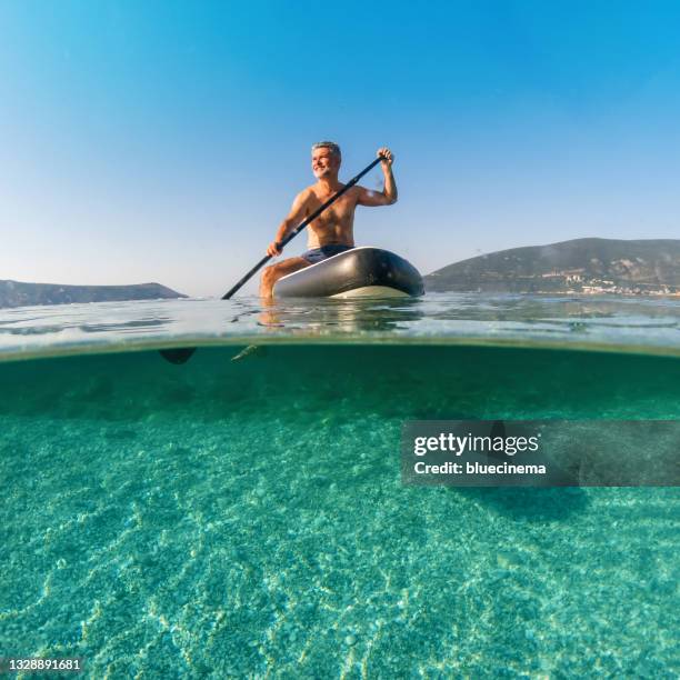 mature man on a paddleboard on the sea in summer - paddle boarding bildbanksfoton och bilder