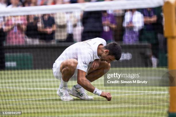 Novak Djokovic of Serbia eats a piece of grass after victory during the Men's Singles Final against Matteo Berrettini of Italy at The Wimbledon Lawn...