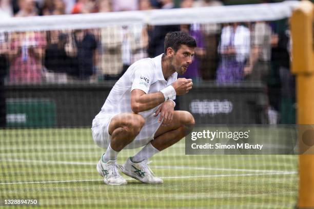 Novak Djokovic of Serbia eats a piece of grass after victory during the Men's Singles Final against Matteo Berrettini of Italy at The Wimbledon Lawn...