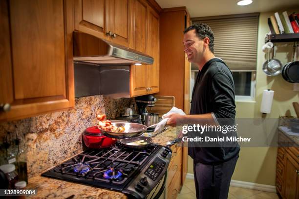 guy with 47xxy having fun while making dinner in his home. - frying pan stock pictures, royalty-free photos & images