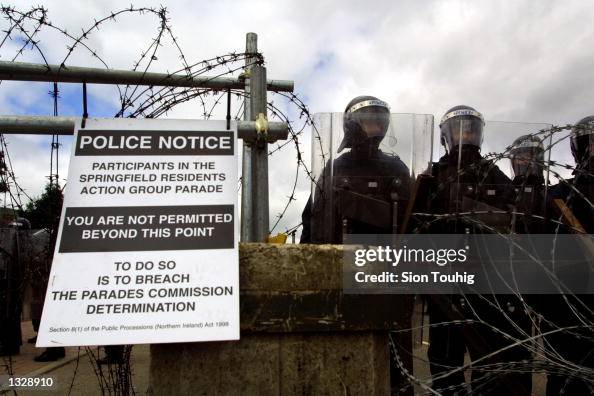 Royal Ulster Constabulary riot police stand guard behind a barricade ...