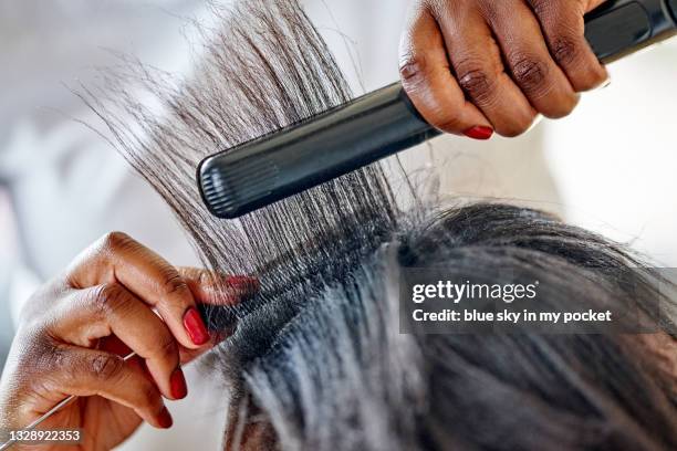 a young woman having her hair straightened. in preparation for hair braids - black hair braiding stock pictures, royalty-free photos & images