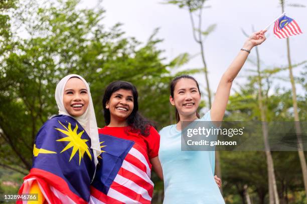 freunde mit malaysischer flagge, die hari merdeka feiert - malaysia stock-fotos und bilder