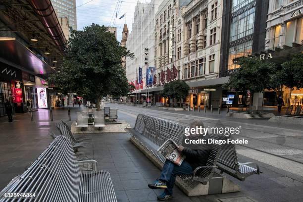 Man is seen reading a newspaper on a empty Bourke Street mall on July 16, 2021 in Melbourne, Australia. Lockdown restrictions have come into effect...